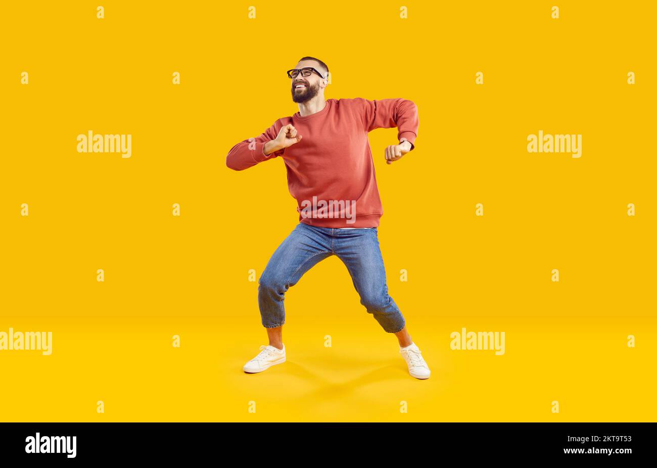 Cheerful active man enjoying life, rejoicing, dancing and having fun on orange background. Stock Photo