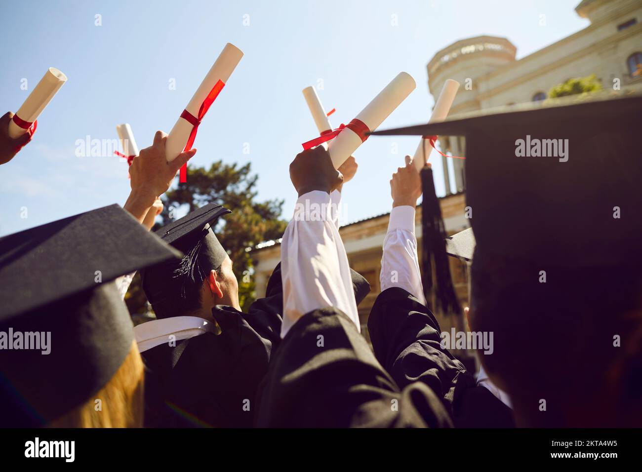 College or university graduates holding up their diplomas during graduation ceremony Stock Photo