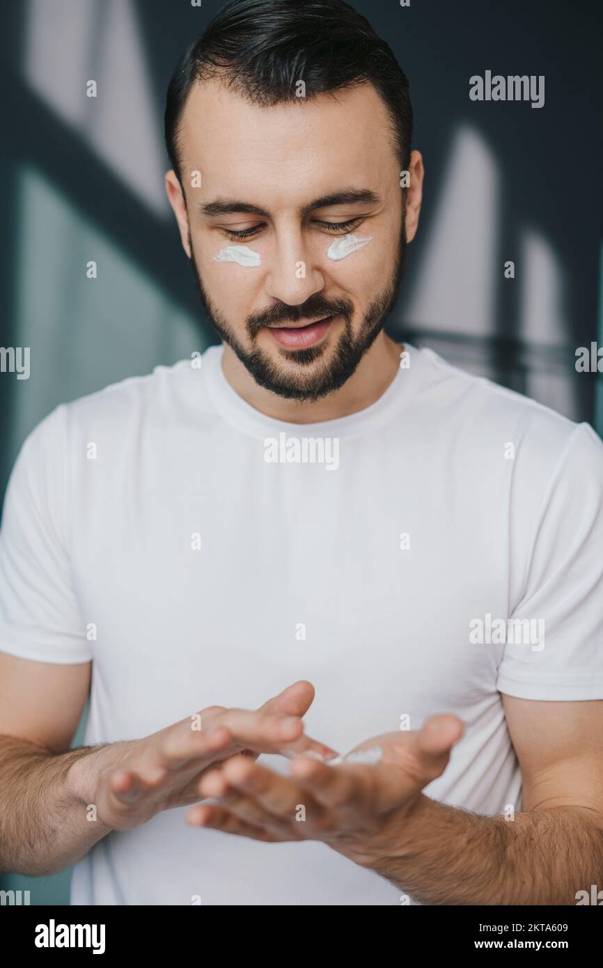 Man taking care of his undereye wrinkles putting anti aging eye moisturizer. Facial skincare