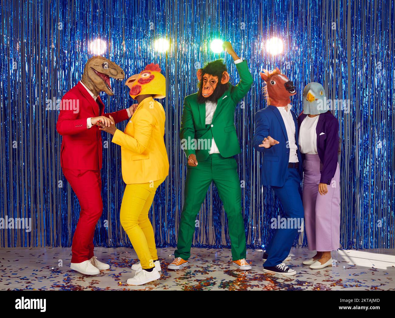 Group of showmen fool around and dance in a club on a shiny blue background. Stock Photo