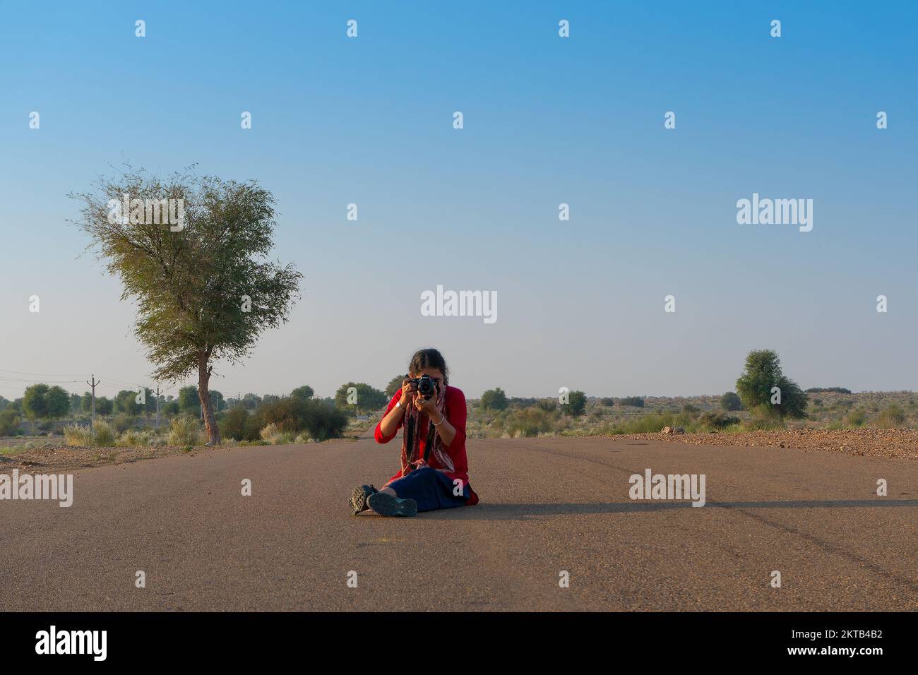 Thar desert, Rajasthan, India - 15th October 2019 : Beautiful happy Indian female tourist posing with camera and enjoying morning in desert on empty h Stock Photo