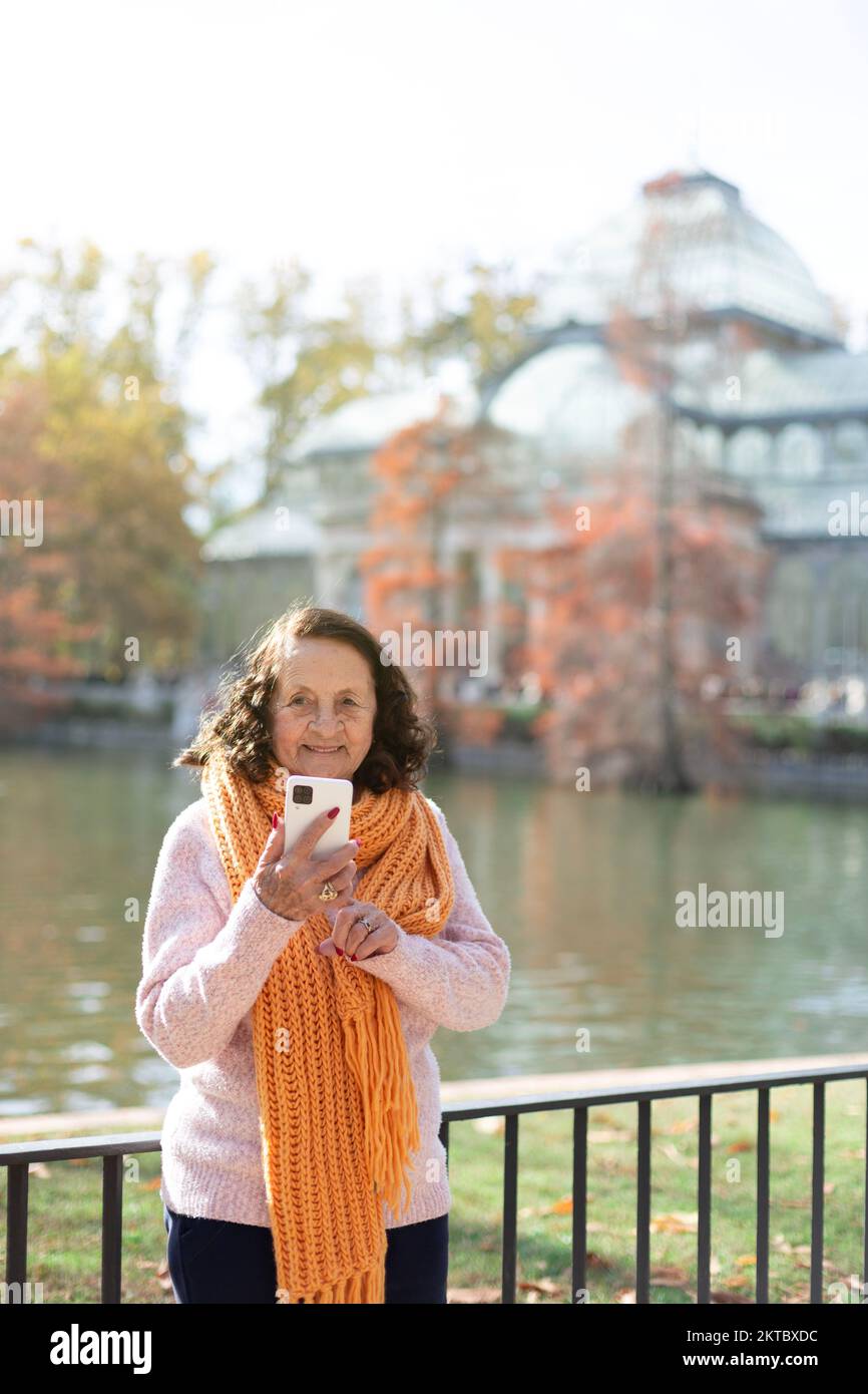 Happy elderly caucasian woman using a smart phone outdoors. Space for text. Stock Photo