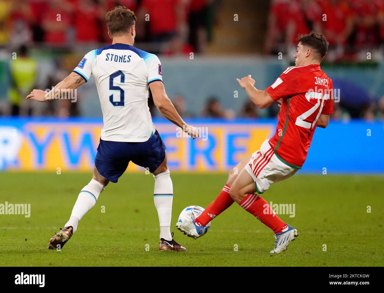 Wales' Daniel James challenges England's John Stones, resulting in a yellow card during the FIFA World Cup Group B match at the Ahmad Bin Ali Stadium, Al Rayyan, Qatar. Picture date: Tuesday November 29, 2022. Stock Photo