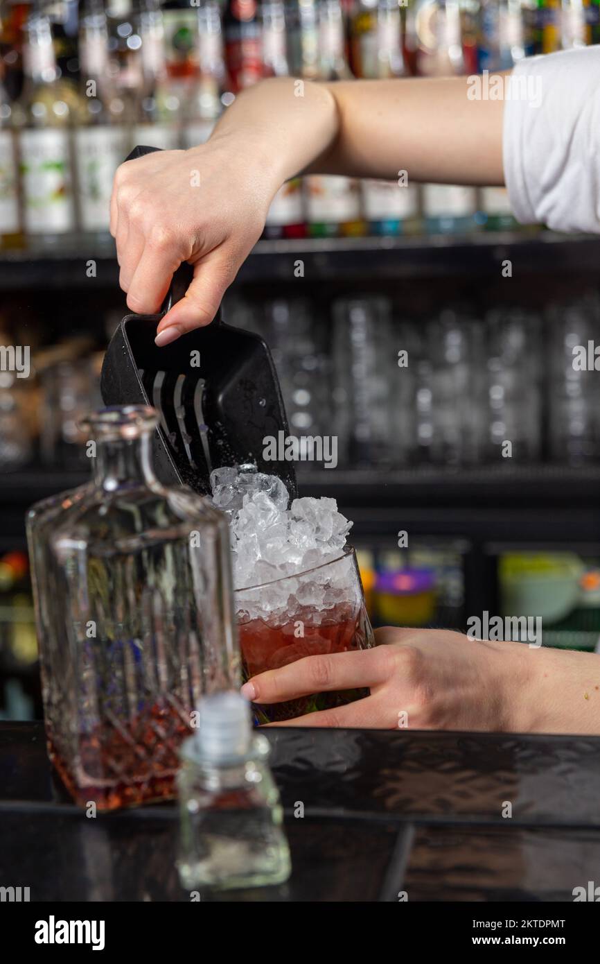 Woman Bartender Pouring Crushed Ice Into Glass On Bar Counter Using A