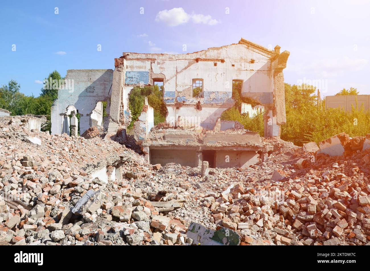 Collapsed industrial multistorey building in daytime. Disaster scene full of debris, broken bricks and damaged non residental house. Concept of war action aftermath or building demolition Stock Photo