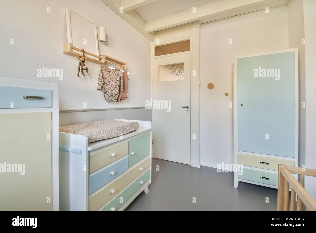 Interior of white room with baby crib near window with blue chest of