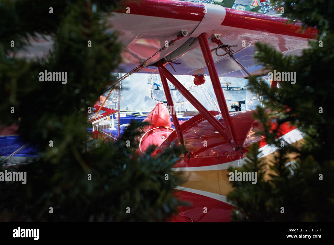 The cockpit of a bright red vintage biplane surrounded by Christmas trees at the Aviation Museum of New Hampshire. Londonderry, New Hampshire. Stock Photo