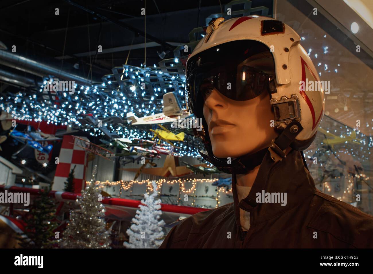 A mannequin dressed in a modern jet pilots uniform and helmet stands in front of a Christmas decorated museum floor at the Aviation Museum of New Hamp Stock Photo