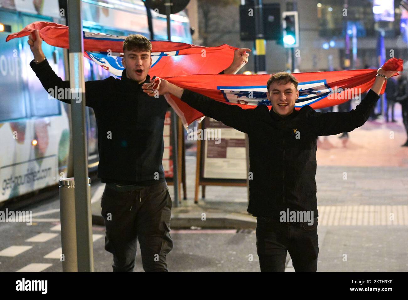 Broad Street, Birmingham, November 29th 2022 - Two England Fans walk joyously home with flags on Broad Street in Birmingham after England beat Wales 3-0 in the World Cup on Tuesday night. Pic by Credit: Sam Holiday/Alamy Live News Stock Photo