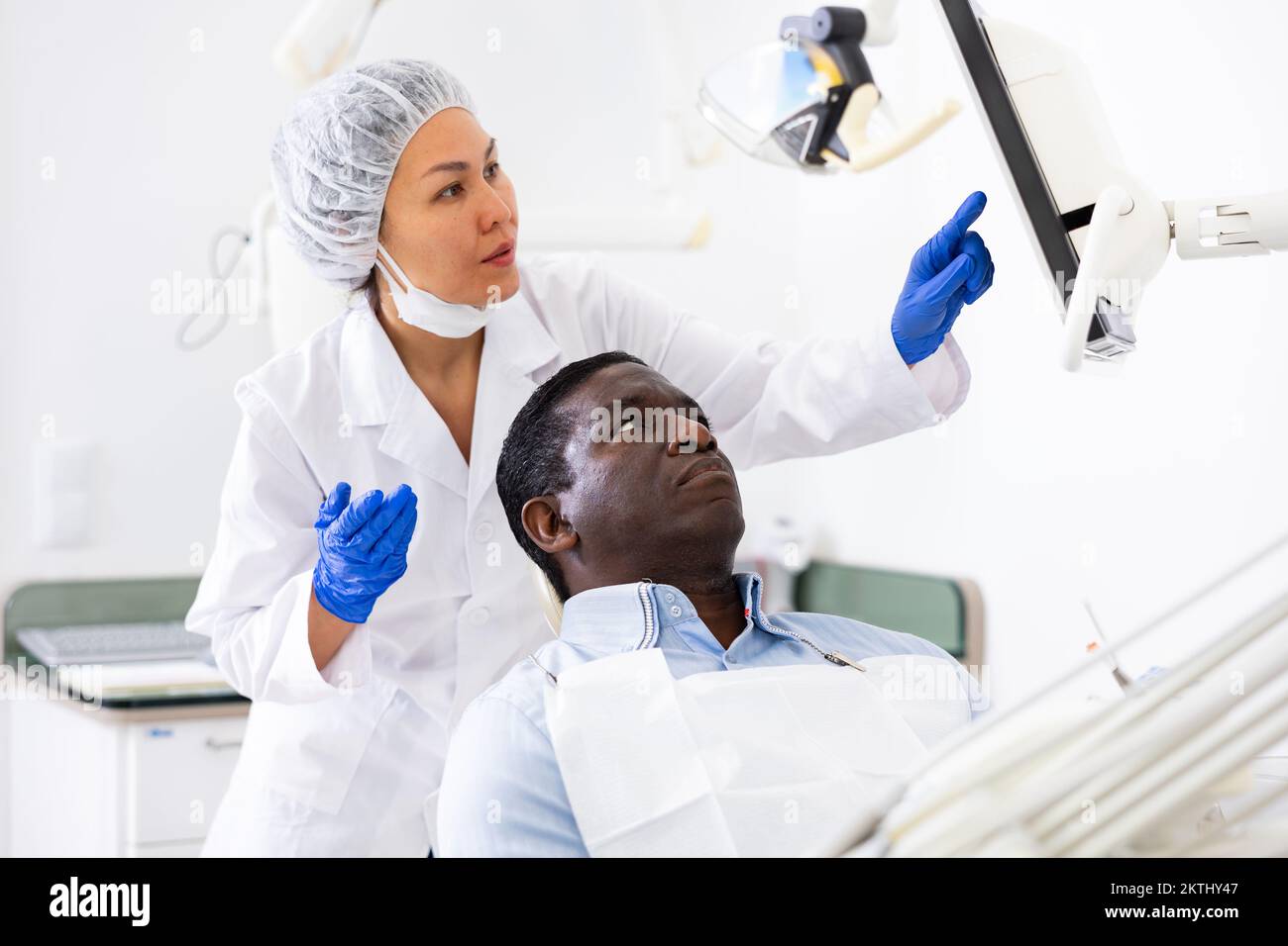 Woman Dentist Pointing At Display To Show Information To Patient Stock 