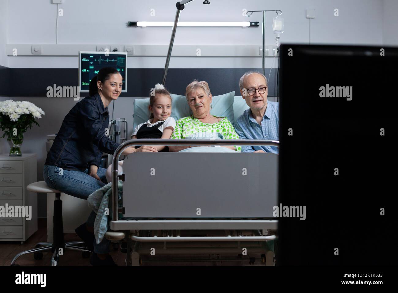 Family watching television in hospital room, grandmother