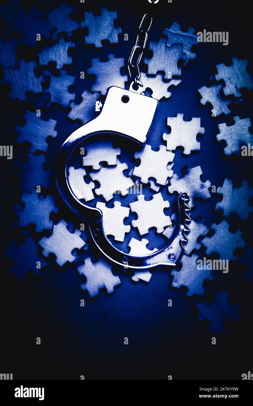 Blue toned still life photo on a scattering of jigsaw puzzles pieces with open cuffs. Open case mystery Stock Photo