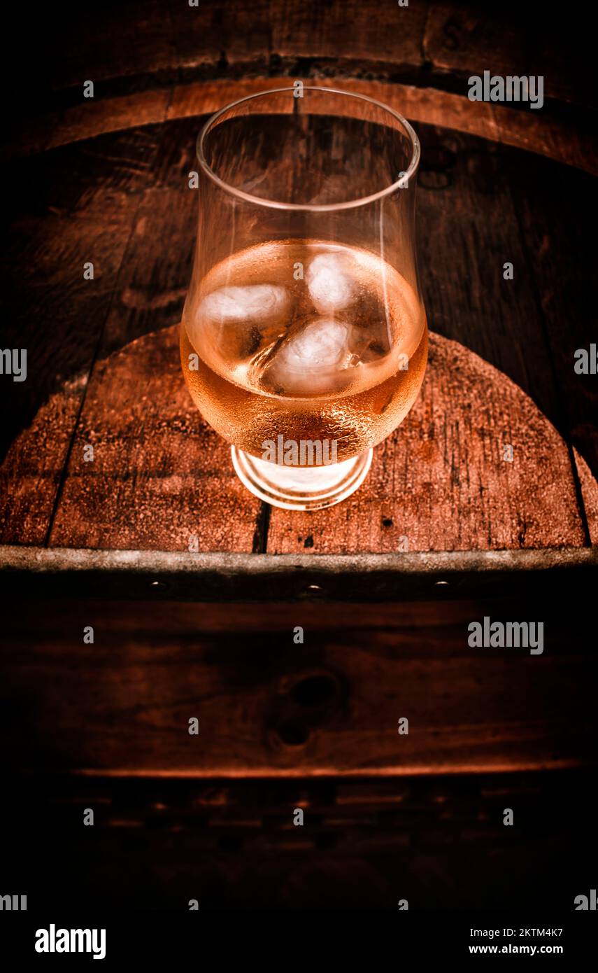 Spirits on the rocks in a snifter glass tumbler on a bar barrel table