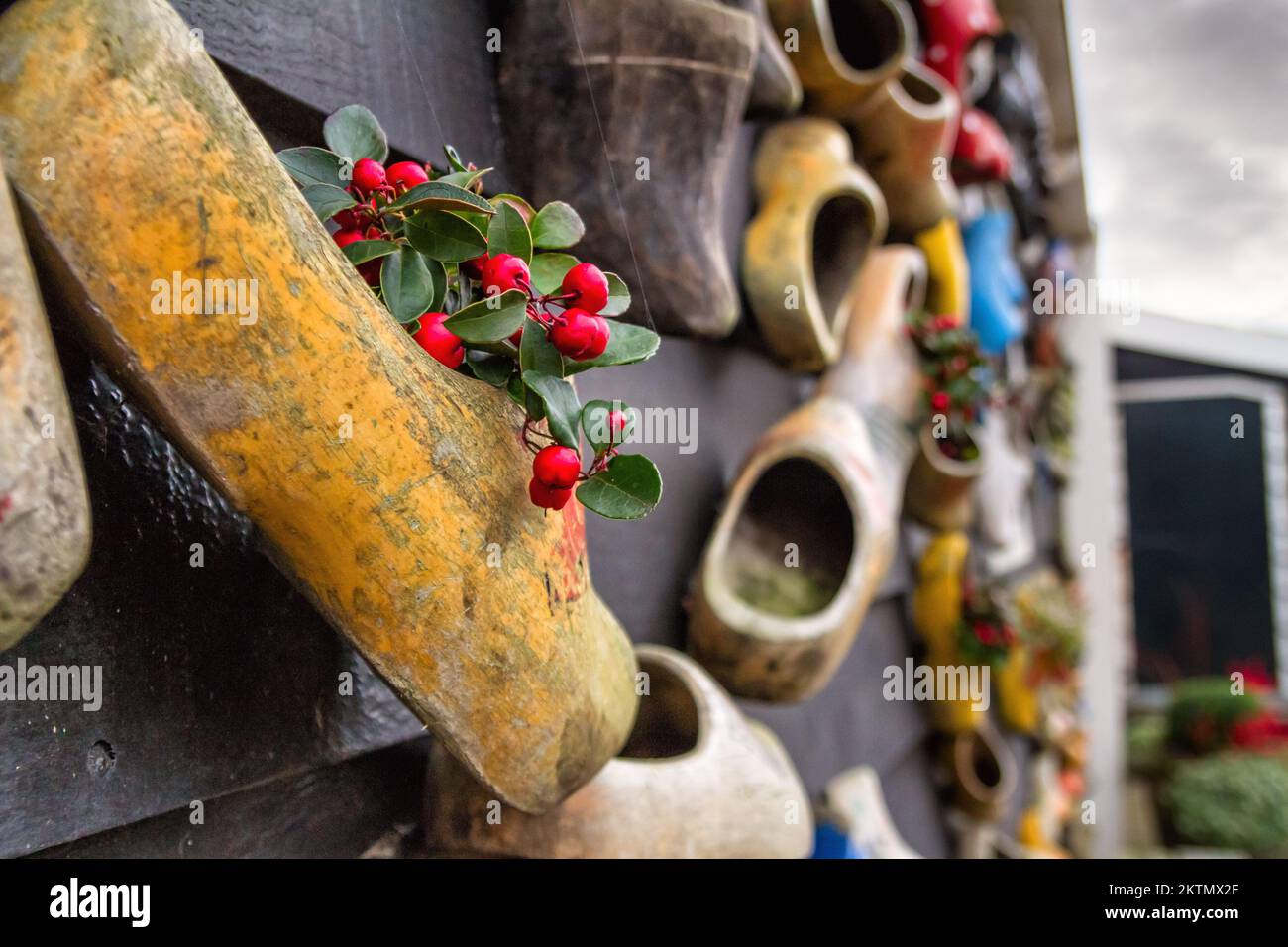 Composition on the wall from traditional dutch wooden shoes - klompen (clogs), decorated with flowers, closeup, the Netherlands Stock Photo