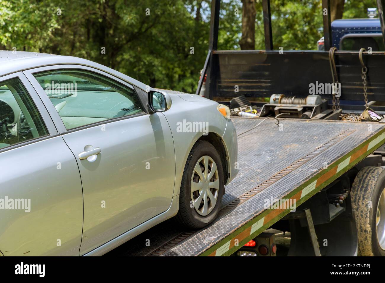 Process of loading damaged, broken car on tow truck working in towing