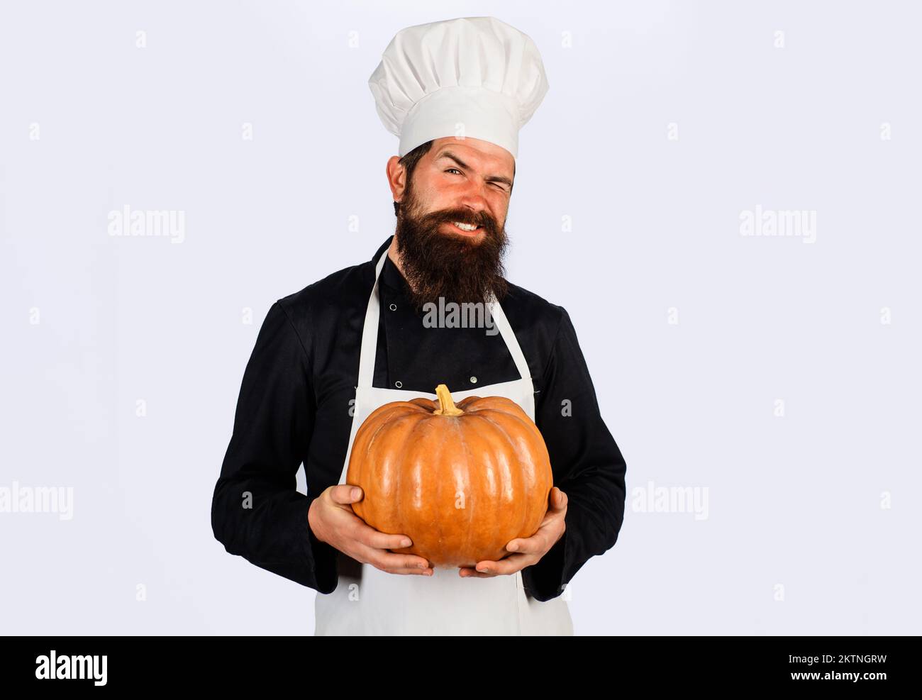 Autumn vegetables. Diet food. Healthy vegetarian eating. Bearded man in chef uniform with pumpkin. Stock Photo