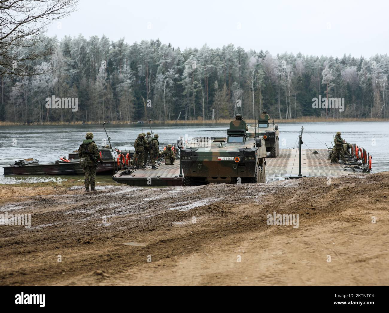 Polish soldiers assigned to 20th Mechanized Brigade utilize a floating pontoon bridge to ferry Armored Multi-Purpose Vehicle (AMPV) across a lake while conducting amphibious assault operations during the Bull Run training exercise at Bemowo Piskie, Poland, Nov. 24, 2022. The 20th Mechanized Brigade is proudly working alongside the 1st Infantry Division, NATO allies and regional security partners to provide combat-credible forces to V Corps, under America's forward deployed corps in Europe. (U.S. Army National Guard photo by Sgt. Gavin K. Ching) Stock Photo