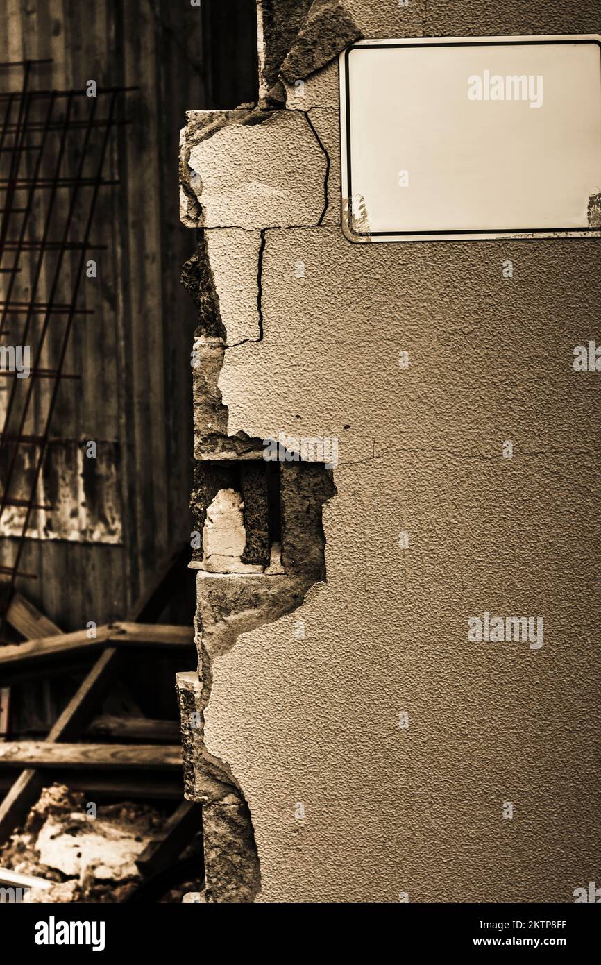 Deserted building details on a destroyed cement wall with blank wall sign. War torn details Stock Photo