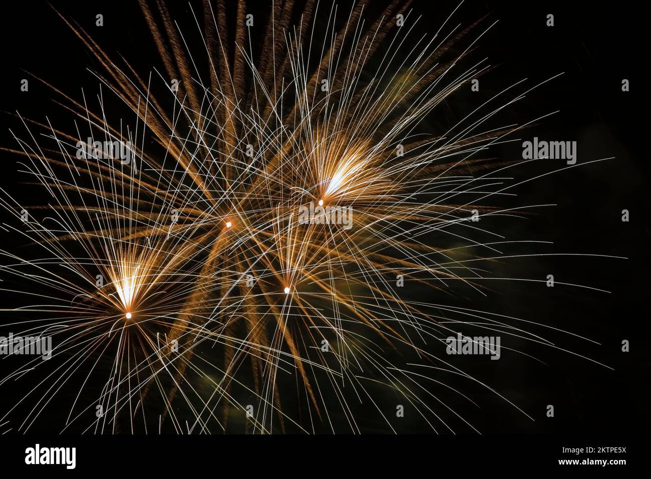 White, gold and yellow fireworks against a black sky background at night. Stock Photo