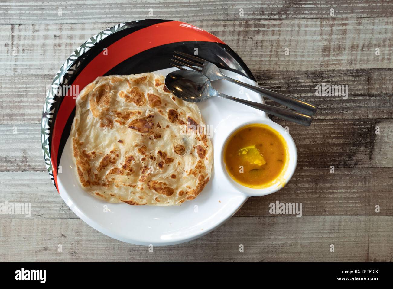 Overhead view of simple no frills roti canai with dhal curry on wooden table Stock Photo