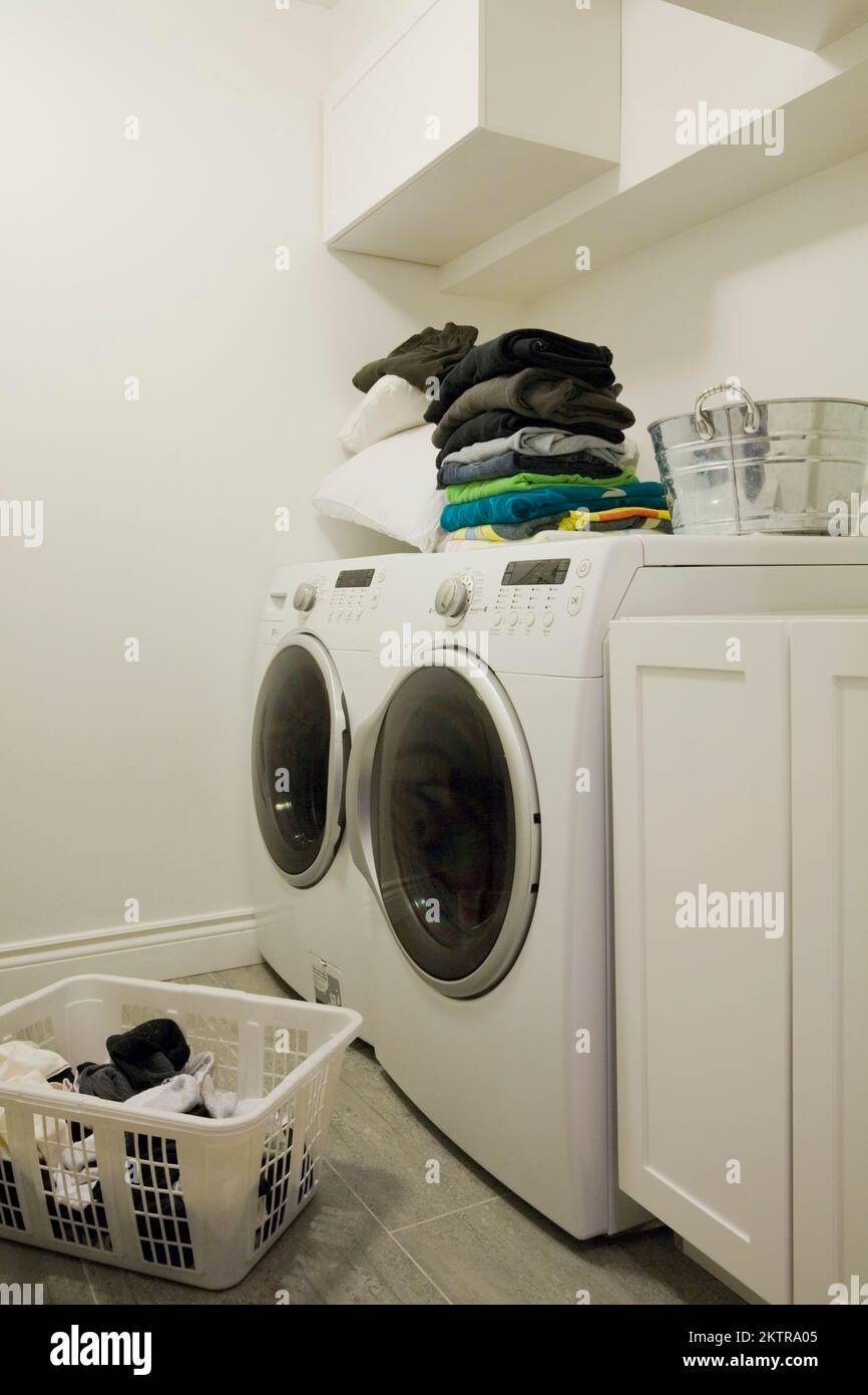 Washer and dryer with dirty clothes hamper in laundry room inside home