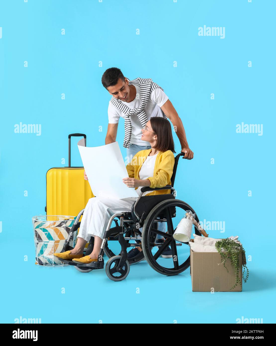 Young man with his wife in wheelchair, moving boxes and house plan on