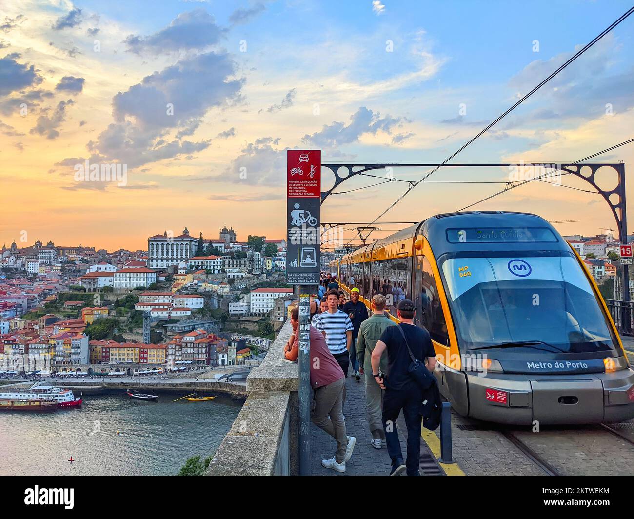PORTO, PORTUGAL - JULY 11, 2022: Metro train on Dom Luis bridge, walking people and sunset, cityscape view with Douro river Ribeira embankment, Porto, Stock Photo