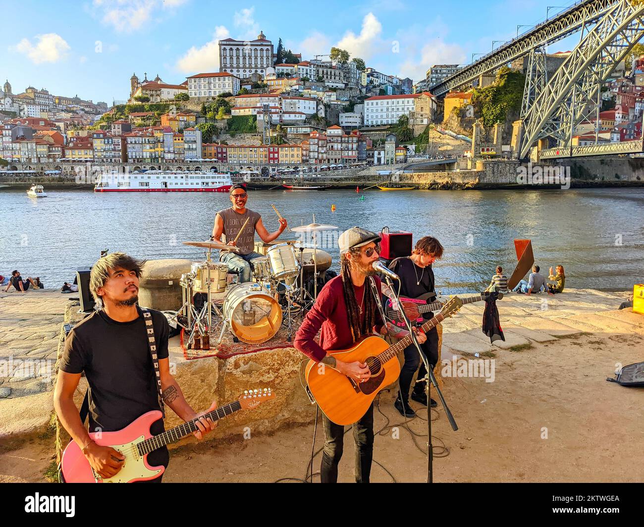 PORTO, PORTUGAL - SEPTEMBER 6, 2022: Street musicians band playing on embankment of Gaia in sunset, downtown cityscape with Ribeira and Dom Luis bridge Stock Photo