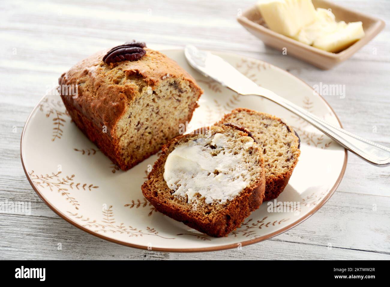 Mini banana loaf slices with butter on pretty plate and knife butter in ...