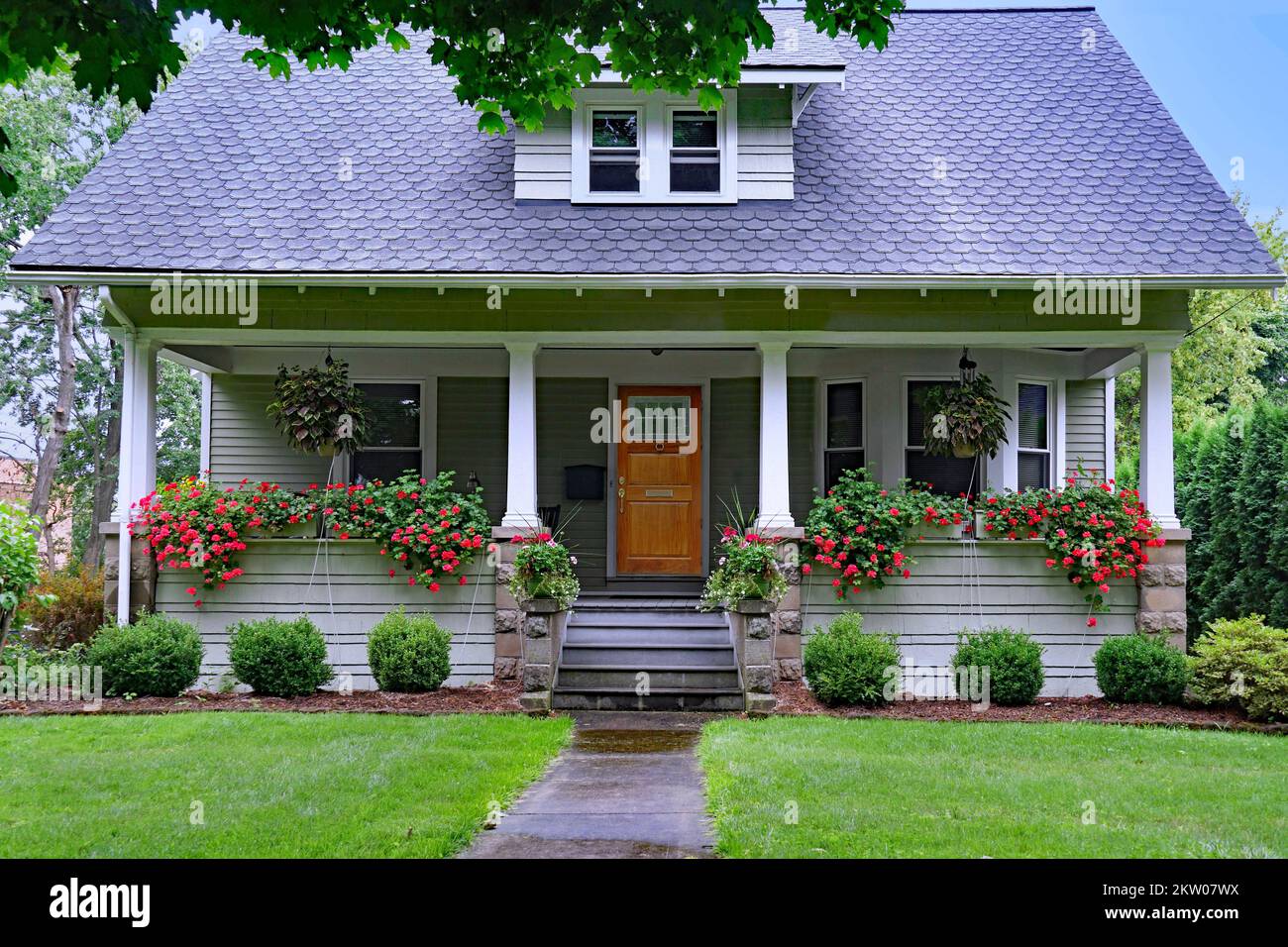 Home with large front porch with baskets of flowers Stock Photo