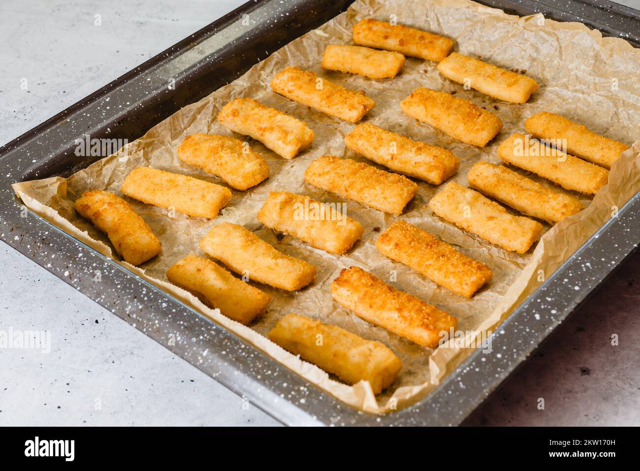 Baking pan with fish sticks close up on the kitchen table. Crunchy