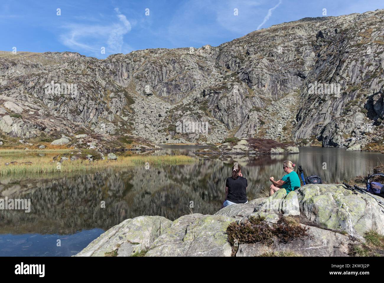 Two Walkers Take a Break at the Étang d'Arbu on the Ascent of the Pic des Trois Seigneurs, Ariège, Pyrenees, France, EU Stock Photo