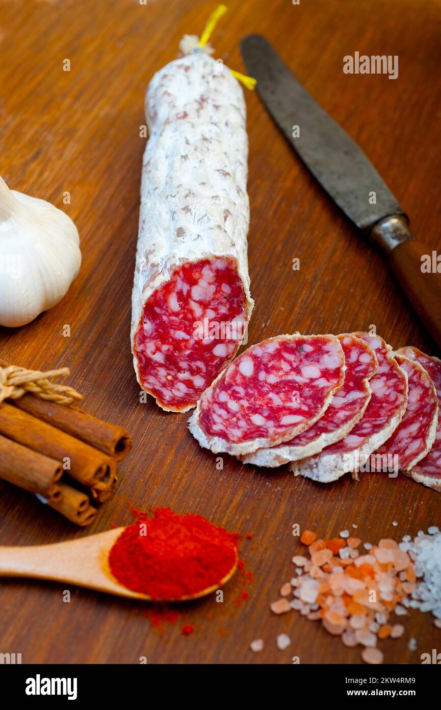Traditional Italian salame cured sausage sliced on a wood board Stock