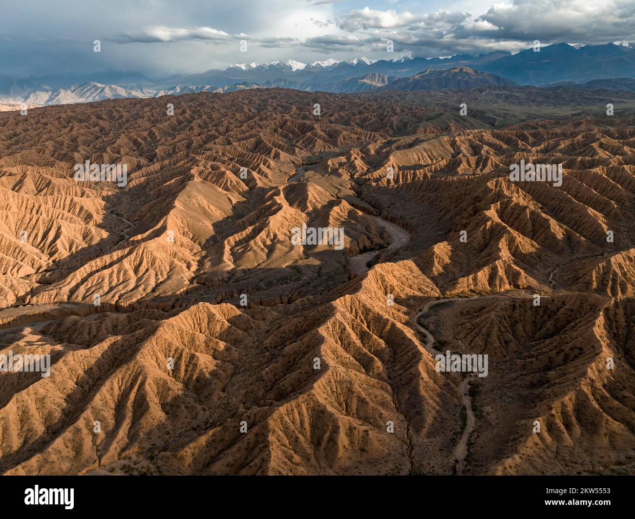 Tianshan Mountains Rivers Aerial view, view over eroded hills towards mountains of the Tian Shan ...