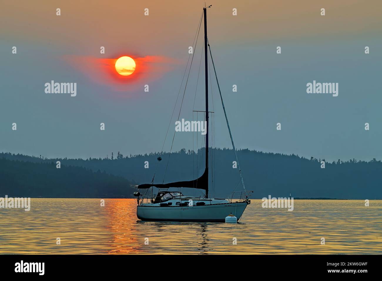 A sail boat moored under a smoke filled sky from the British Columbia wildfires off the coast of Vancouver Island Stock Photo