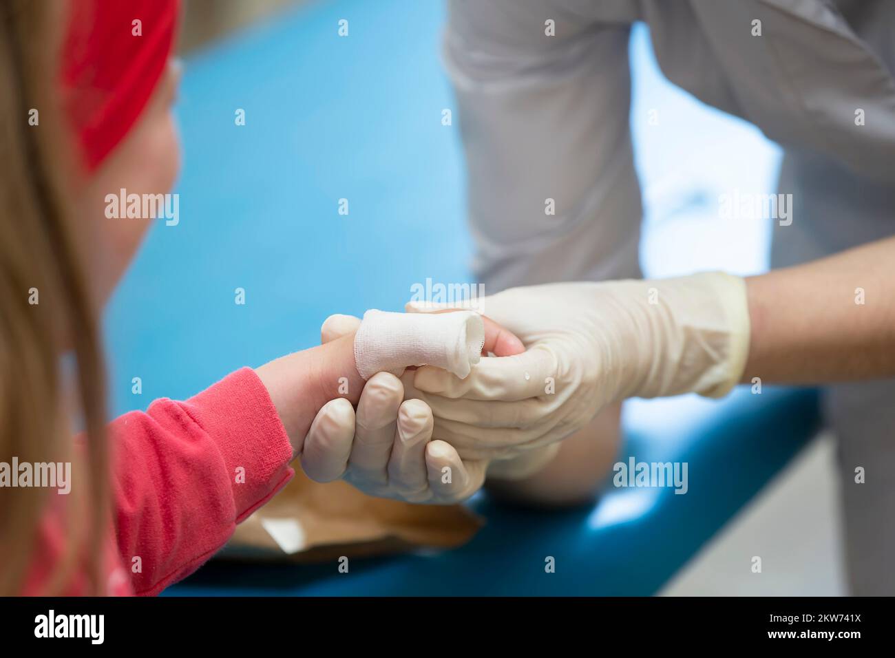 The hands of the doctor bandage the sore finger with a bandage of the