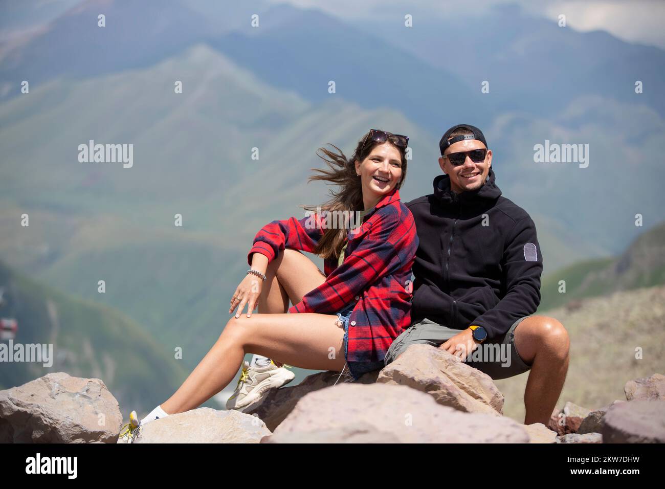 Happy couple man and woman hikers on the top of the mountain, enjoying ...