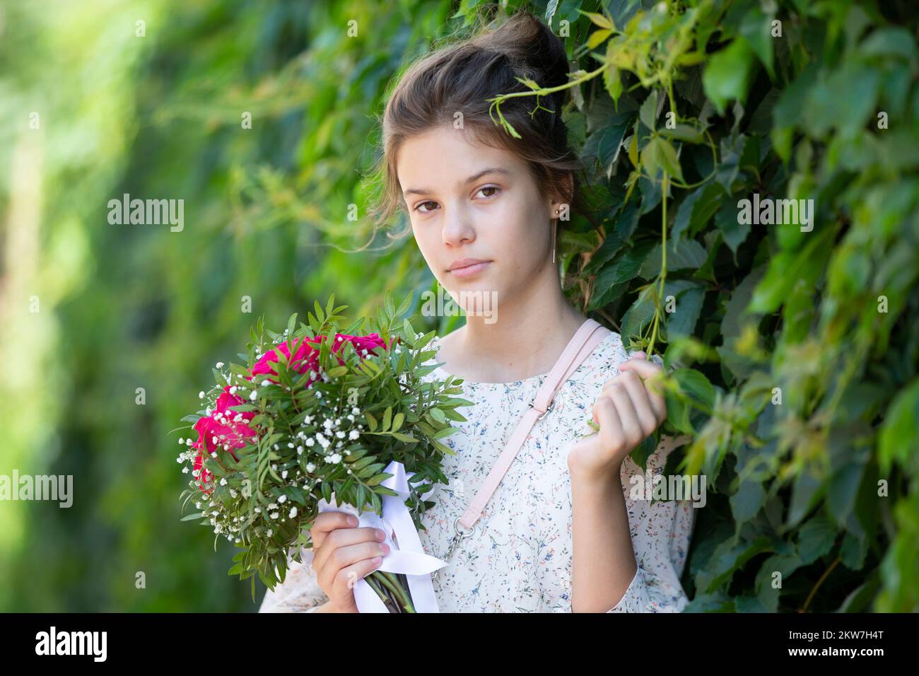 A brunette teenager girl with a bouquet of summer flowers poses for the ...