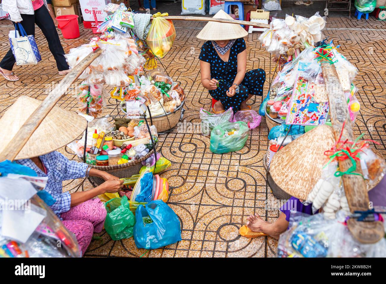Vietnamese traders wearing bamboo hat, preparing food for panniers, Bin