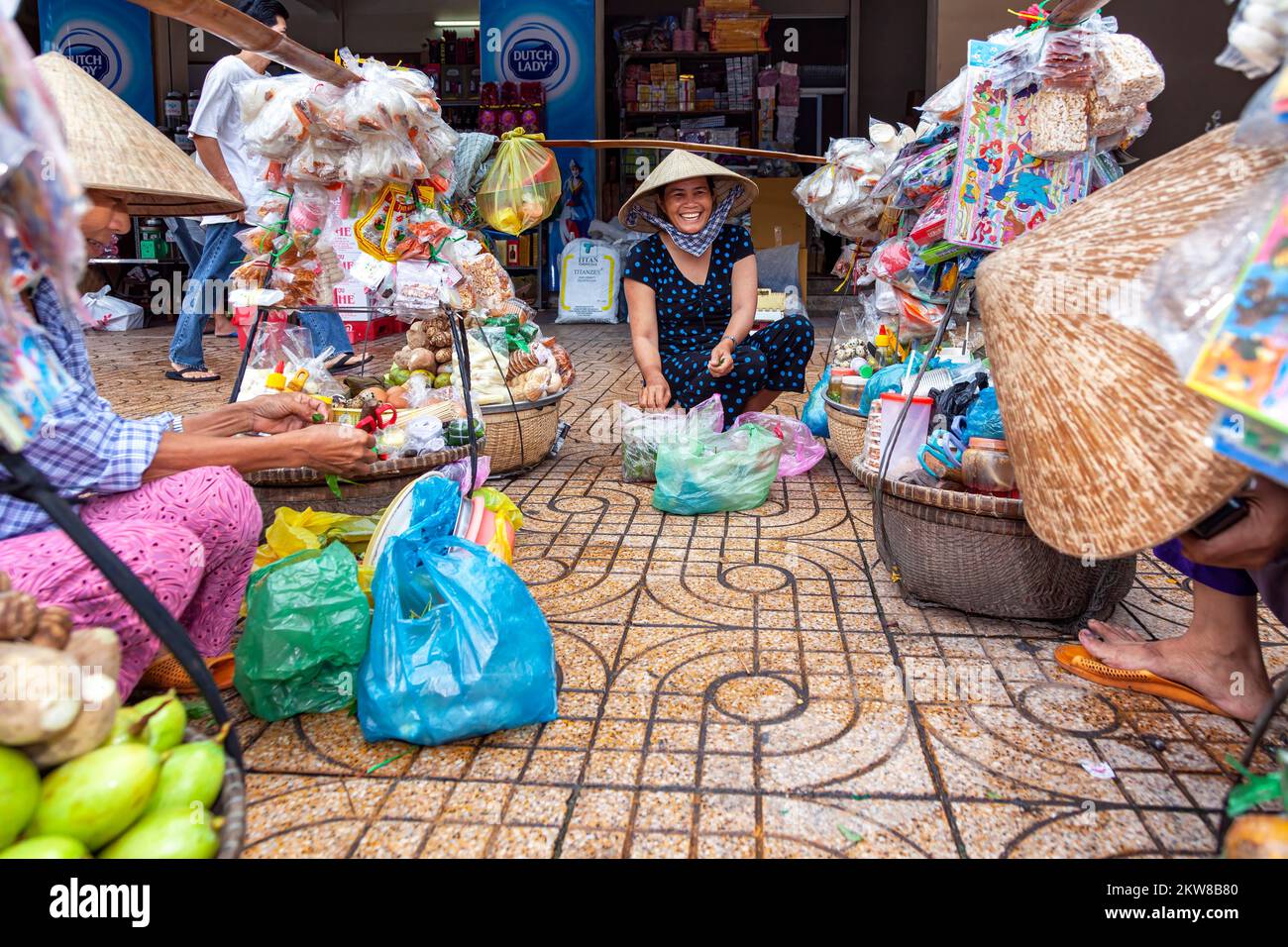Vietnamese traders wearing bamboo hat, preparing food for panniers, Bin
