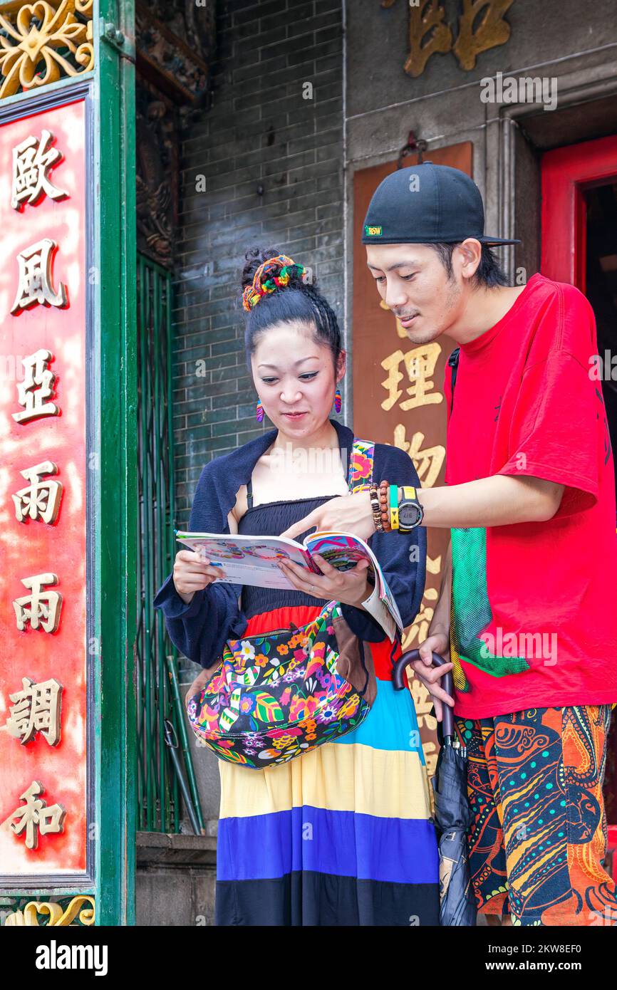 Asian tourist couple reading tour guide book, Hoi Quan Tue Thanh temple, Ho Chi Minh City, Vietnam Stock Photo