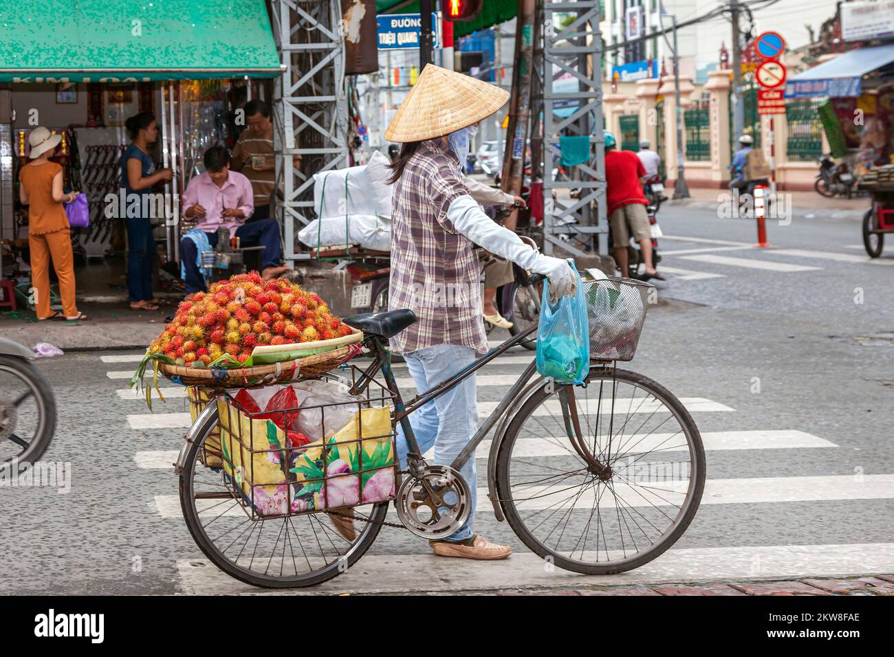 Vietnamese lady vendor wearing bamboo hat, with bicycle, Ho Chi Minh City, Vietnam Stock Photo