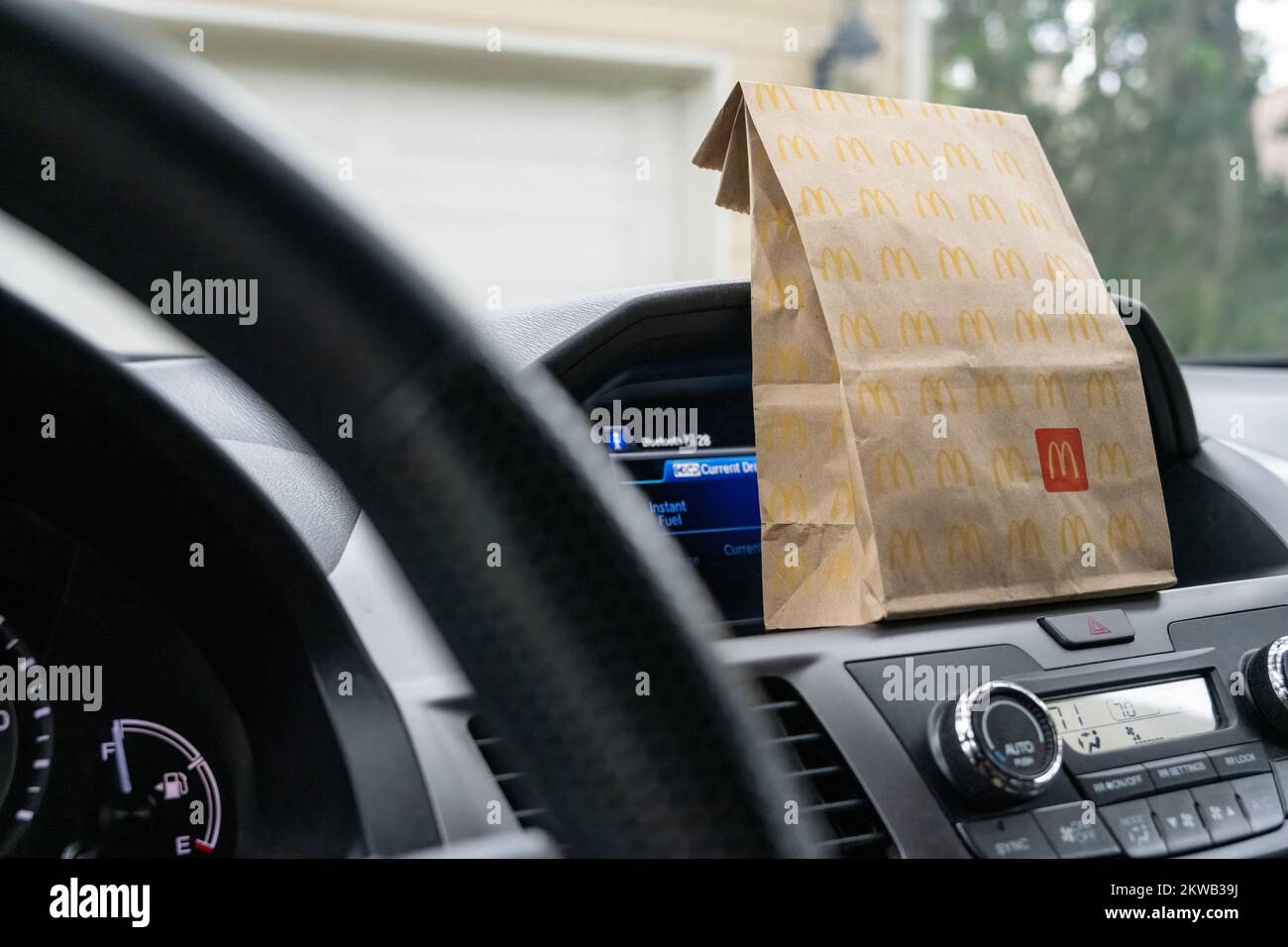McDonald's fast food bag on the dash of a van parked in front of a home garage. (USA) Stock Photo