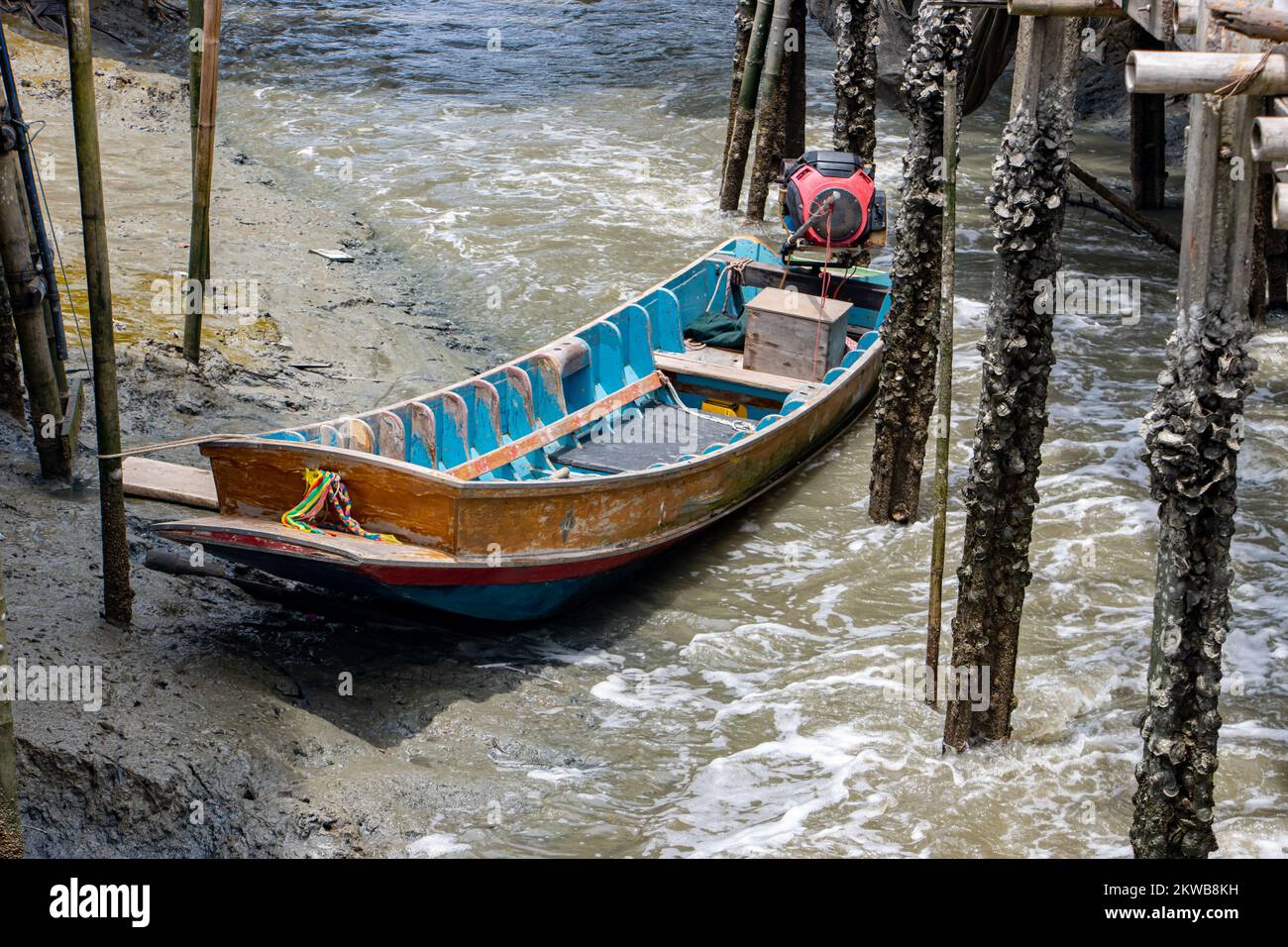 An wooden boat with the engine is moored in the water canal, Thailand ...
