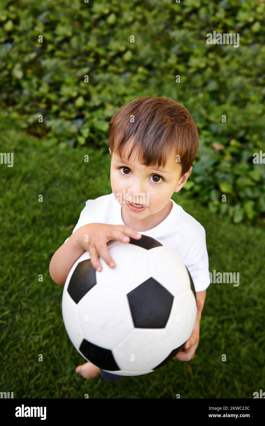Shoot for your goals. an adorable little boy playing with a soccer ball outside. Stock Photo