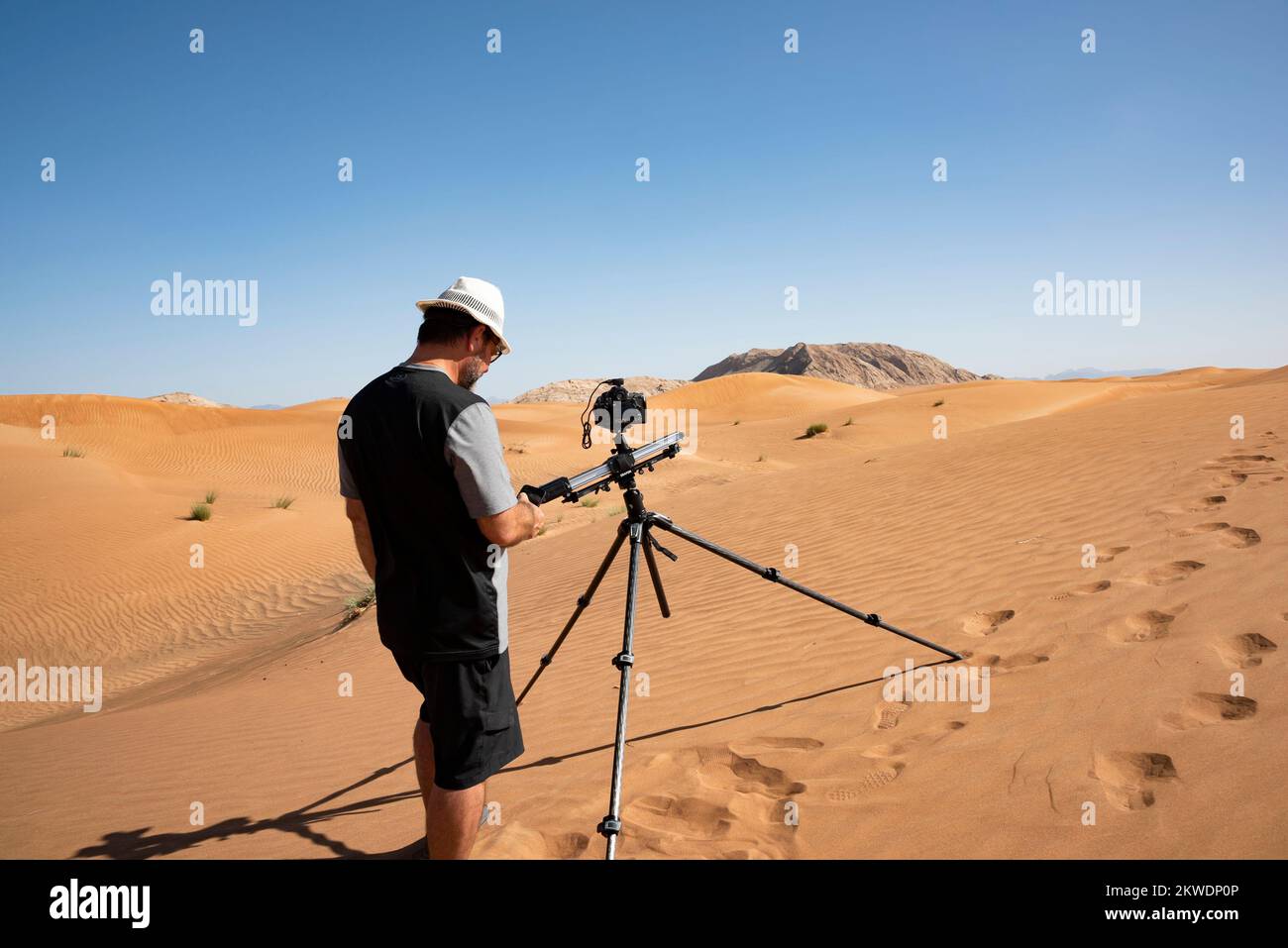 Man in the desert using a motorized slider to take pictures, to shoot videos or for production of a timelapse illustrative editorial Stock Photo