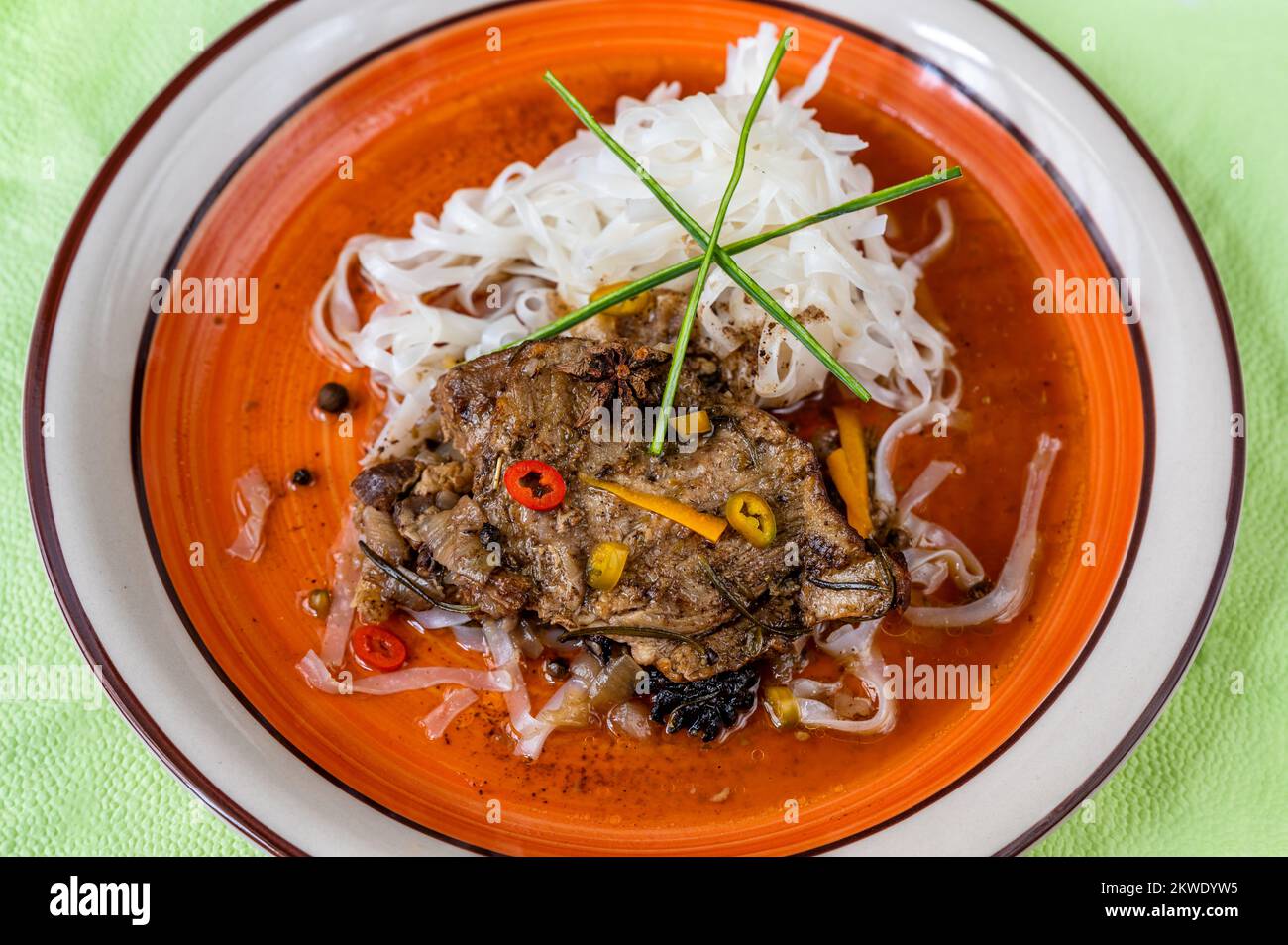 Slice of spicy beef with rice noodle on orange plate, closeup. Stock Photo