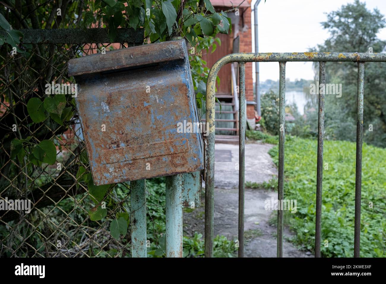 Mailbox is hanging on the fence. Old, rusty mailbox with peeling paint. Stock Photo