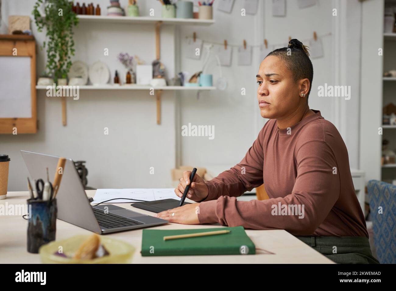 Side view portrait of black young woman using pen tablet while working ...