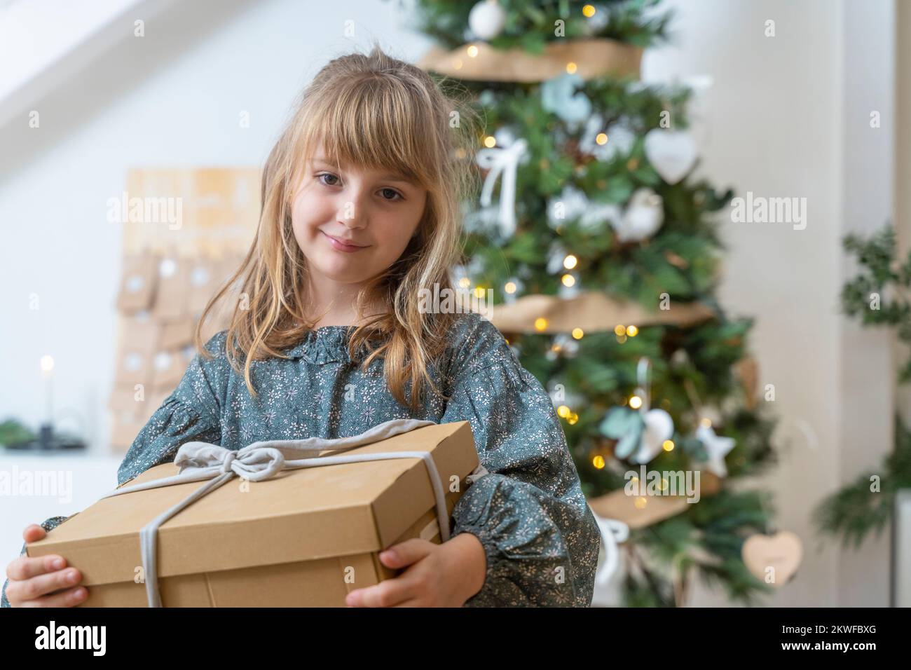 Little girl with a gift near the Christmas tree at home Stock Photo